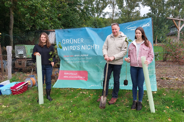 Teilnehmer am Einheitsbuddeln stehen mit Setzlingen und Spaten vor einem Banner von strom_regional.